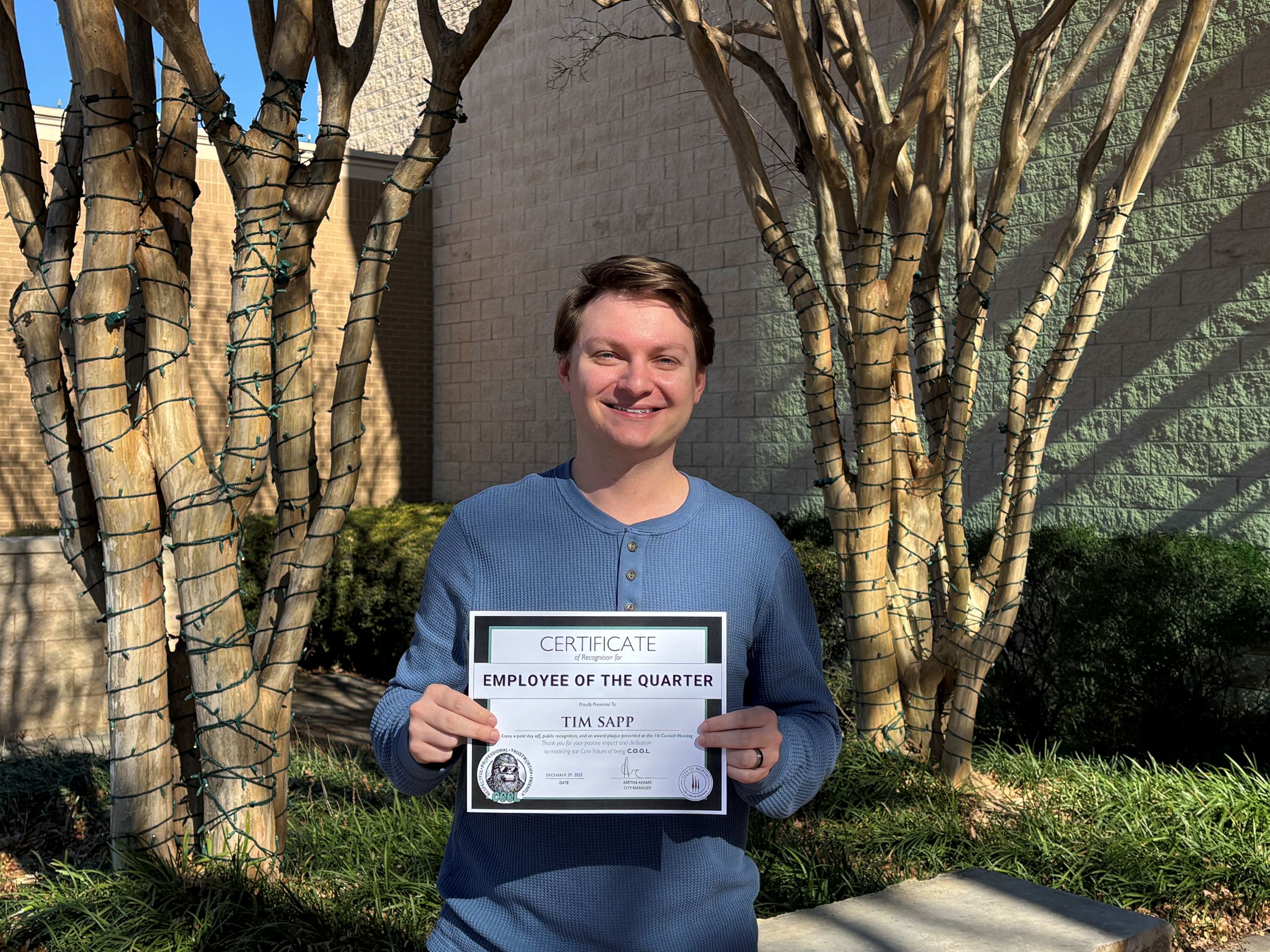 Tim Sapp - young man posing for a photo while holding an employee of the quarter certificate outside